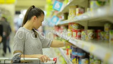 穿休闲服装的年轻妻子正在<strong>超市货架</strong>旁选择食品。